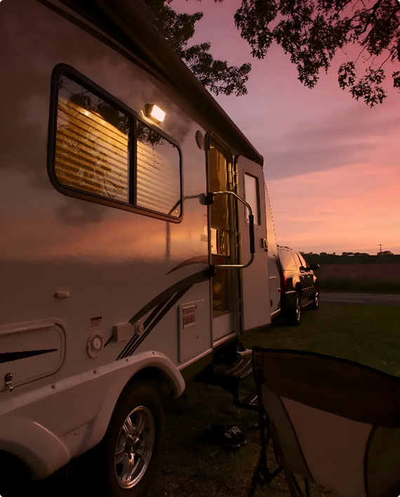 Camper trailer at sunset with trees.