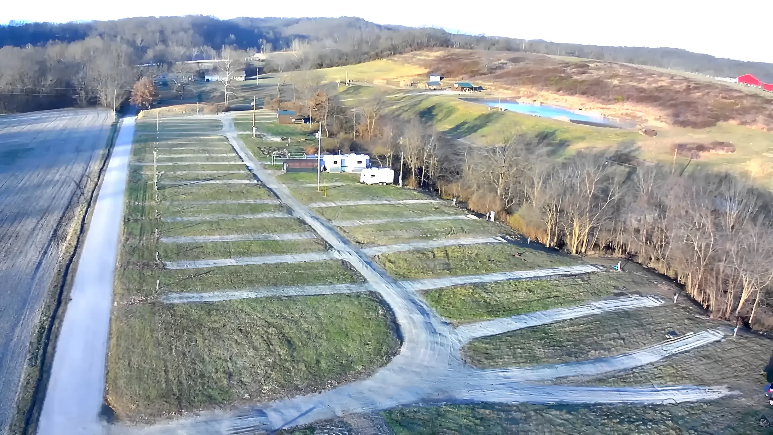 Empty campground with surrounding trees and hills.